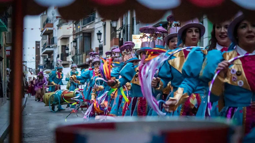 Desfile con trajes coloridos y cintas en una calle urbana
