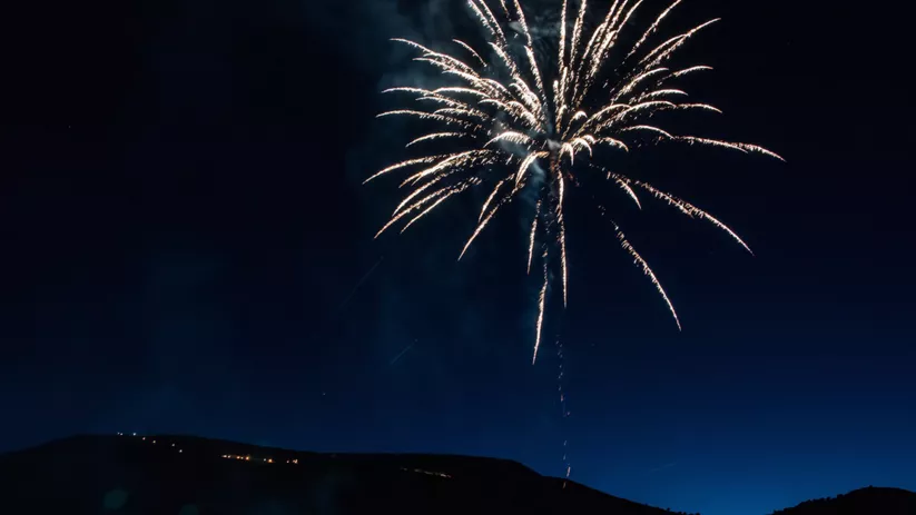 Fuegos artificiales iluminando el cielo nocturno sobre una colina