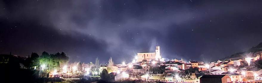 Vista nocturna de un pueblo iluminado bajo un cielo estrellado
