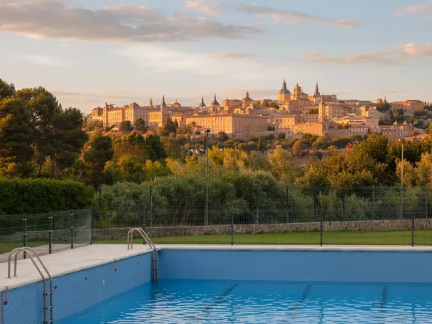 Piscina con vistas a ciudad histórica al atardecer.