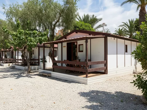 Fila de bungalows blancos entre árboles y grava