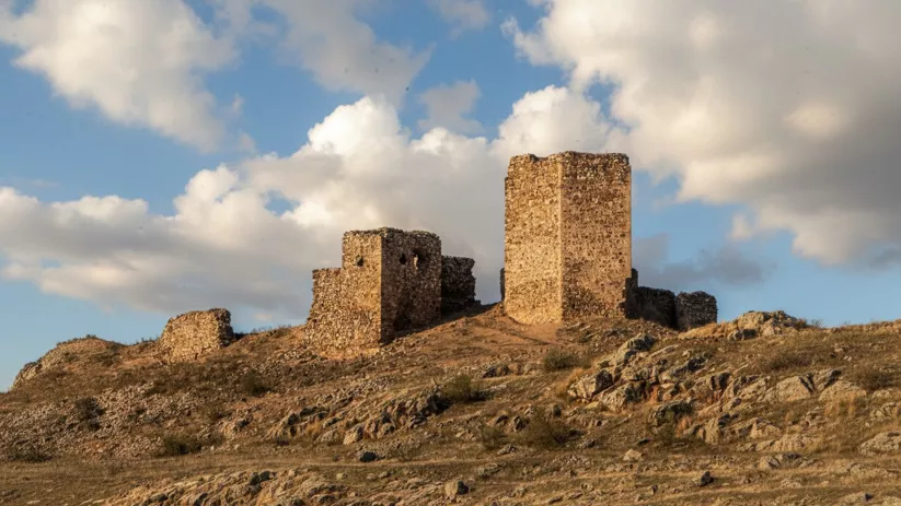 Ruinas del castillo de Caracuel de Calatrava sobre una colina rocosa al atardecer.