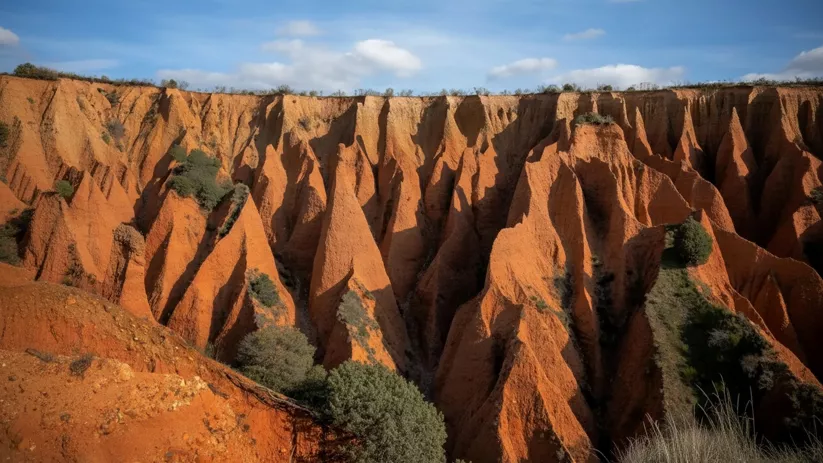 Barrancos erosionados bajo cielo azul.