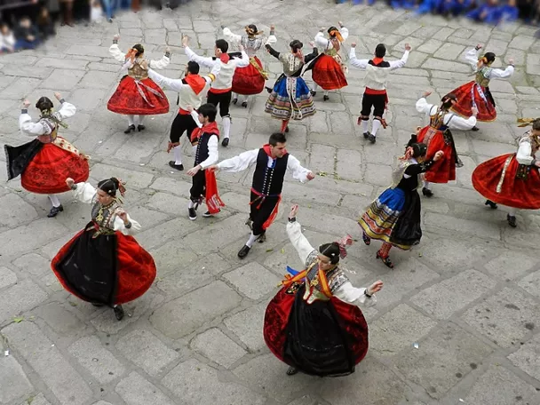 Grupo de baile con trajes tradicionales en corro al aire libre.