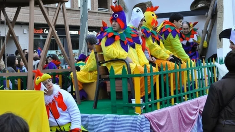 Grupo disfrazado de gallinas sobre carroza durante desfile de carnaval.