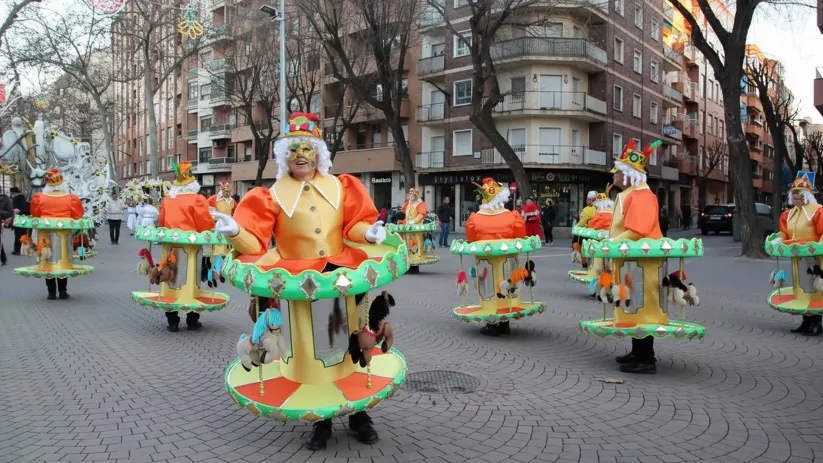 Personas con disfraces de carrusel participando en pasacalles.