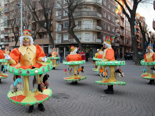 Personas con disfraces de carrusel participando en pasacalles.
