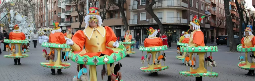 Personas con disfraces de carrusel participando en pasacalles.