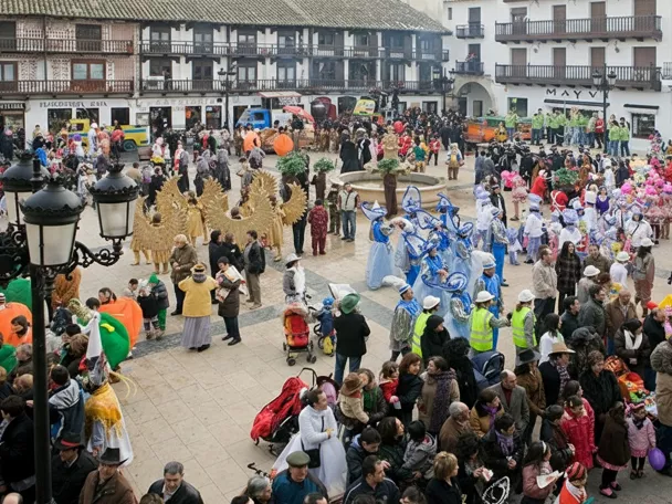 Comparsas con trajes llamativos reunidas alrededor de una fuente.