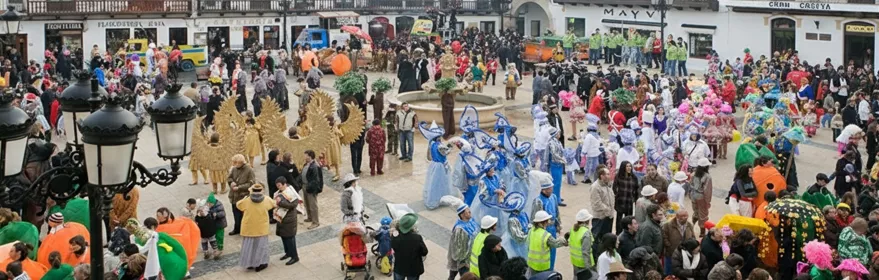 Comparsas con trajes llamativos reunidas alrededor de una fuente.