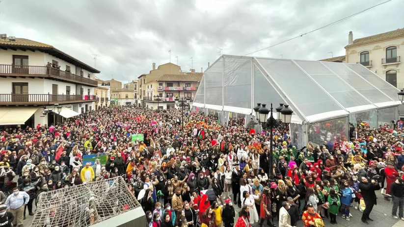 Plaza llena de personas disfrazadas durante una celebración multitudinaria.