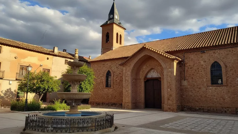 Plaza de Carrizosa con fuente central y fachada de la iglesia parroquial al fondo.