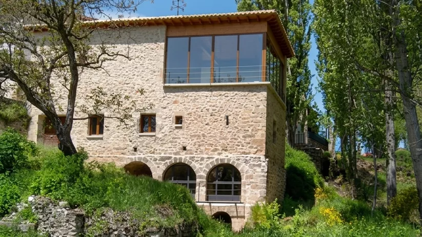 Casa de piedra junto a río y vegetación