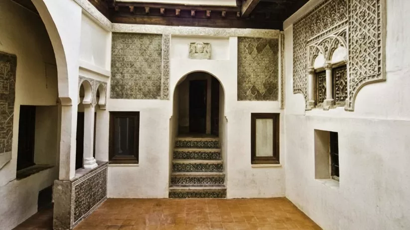 Patio interior con arcos decorativos, yeserías y escalinata central.