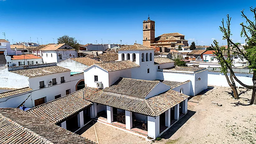 Vista aérea de conjunto de casas blancas con tejados de teja y torre al fondo.