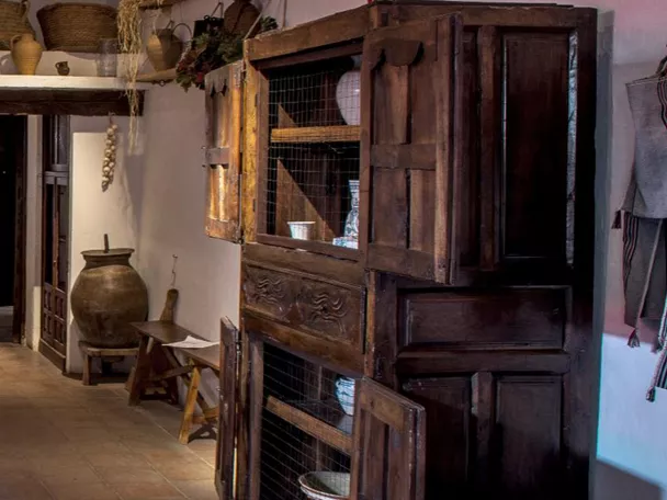 Interior de cocina tradicional con mesa preparada y vasijas de barro.