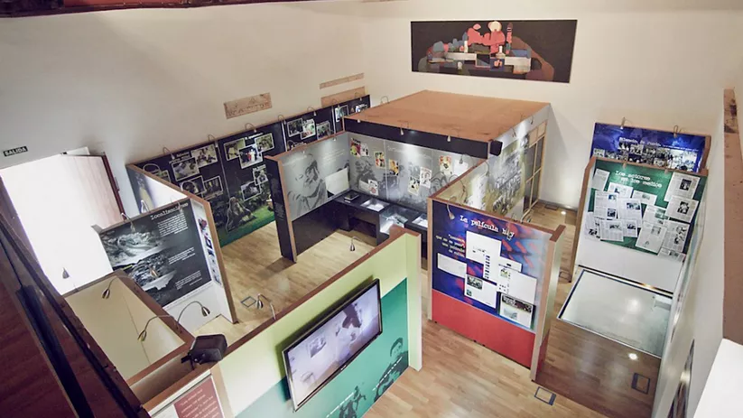 Sala expositiva con paneles informativos, vitrinas y suelo de madera.