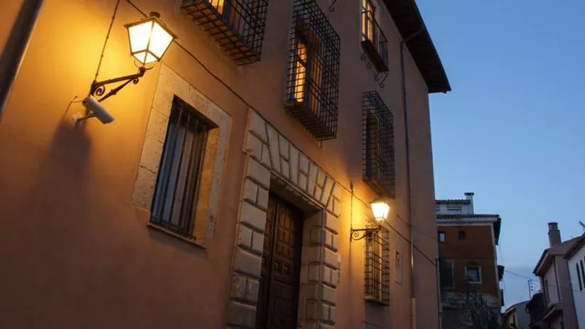 Edificio iluminado al anochecer con faroles encendidos.
