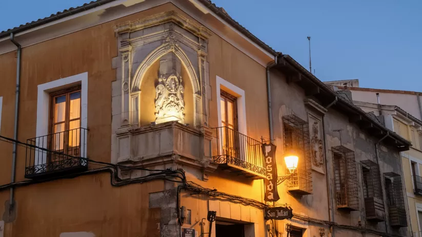 Edificio histórico iluminado con balcones y escudo en esquina