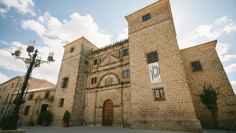 Palacio de piedra con torres, gran portada y plaza despejada