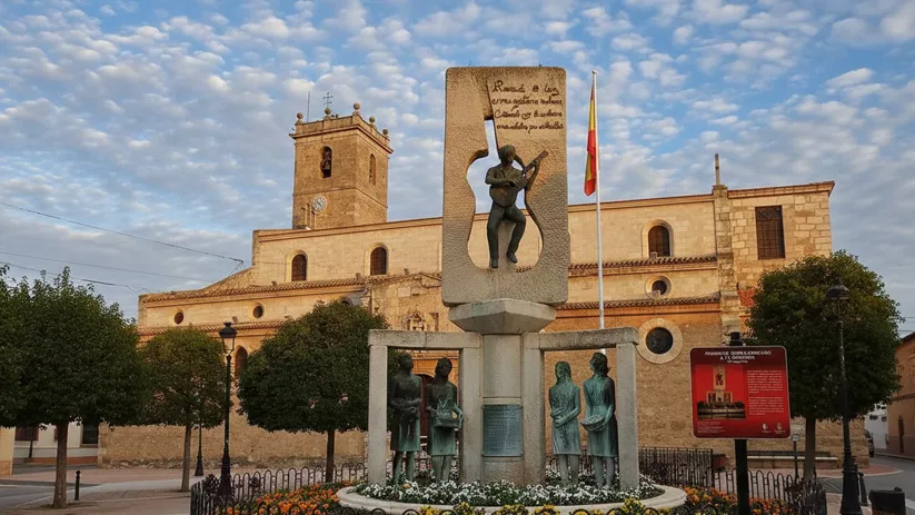 Escultura central frente a un templo de piedra al atardecer.
