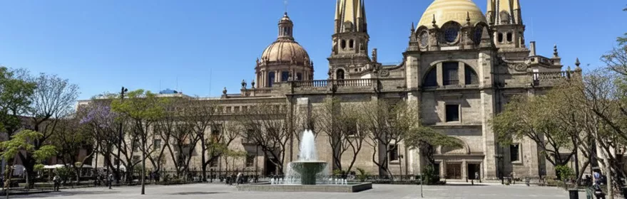 Plaza amplia con fuente central y catedral de torres altas.