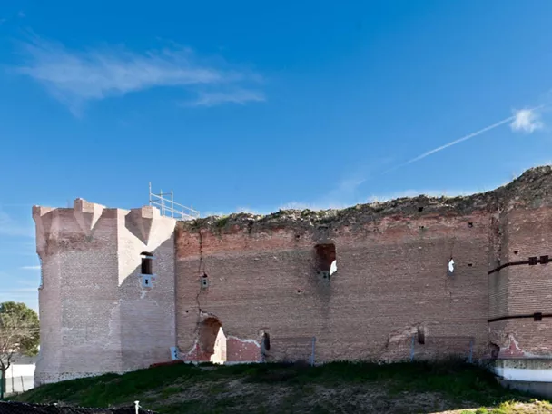 Muralla de ladrillo con torre circular y restos defensivos