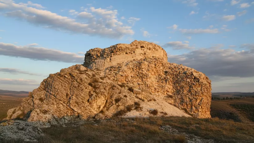 Restos de muralla sobre peñasco al atardecer.