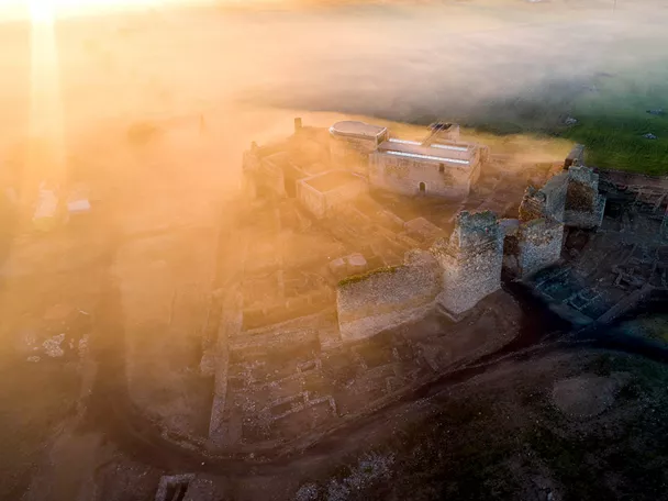 Vista aérea de fortaleza medieval entre la niebla al amanecer