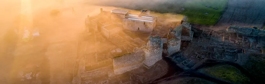 Vista aérea de fortaleza medieval entre la niebla al amanecer