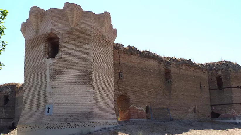 Torre defensiva de planta cuadrada con almenas y ventana estrecha.