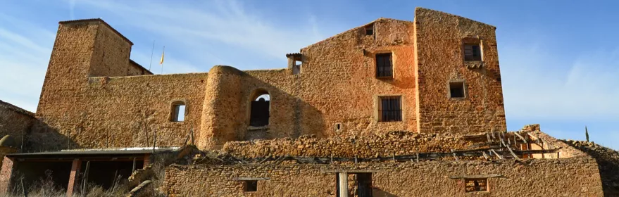 Fortaleza de piedra sobre colina bajo cielo azul.