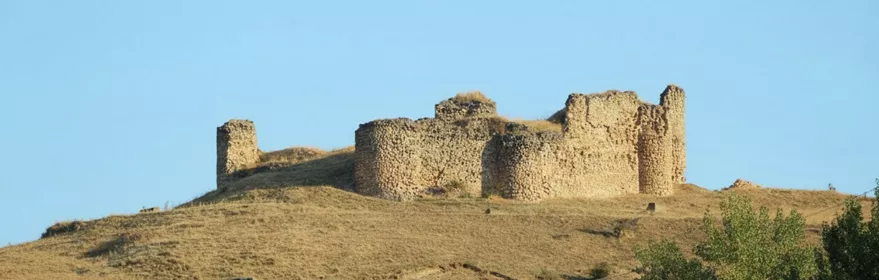 Ruinas de fortaleza en lo alto de una colina seca.