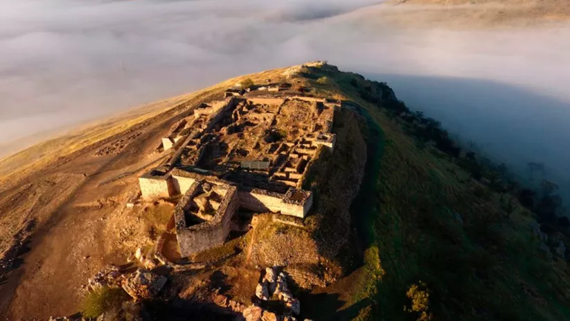Ruinas de recinto fortificado sobre una elevación envuelta en bruma