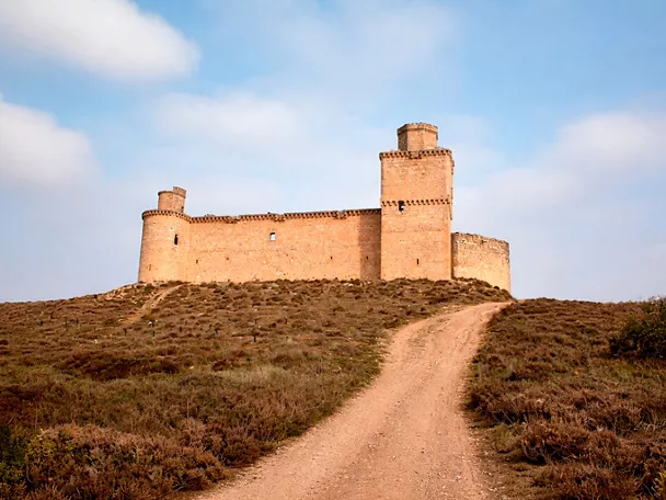 Castillo de piedra sobre colina con camino de acceso
