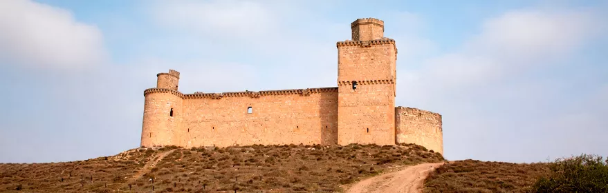Castillo de piedra sobre colina con camino de acceso