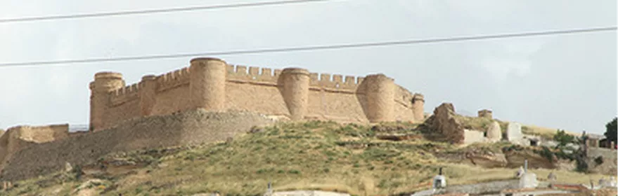 Vista lejana de una fortaleza amurallada dominando el paisaje rural