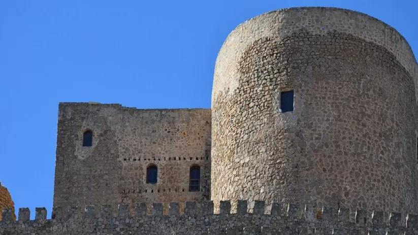Torre circular y muralla de piedra vistas desde el exterior.