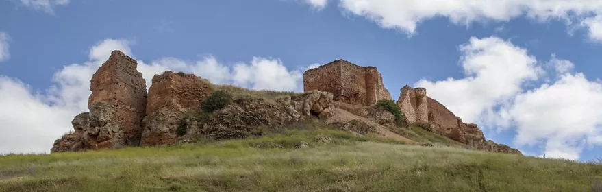 Ruinas de castillo medieval sobre una colina herbosa.