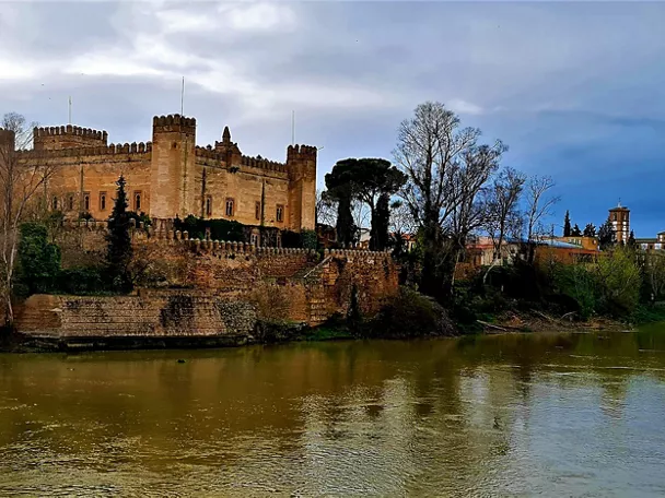 Fortaleza de piedra junto a un río rodeada de vegetación