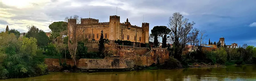 Fortaleza de piedra junto a un río rodeada de vegetación