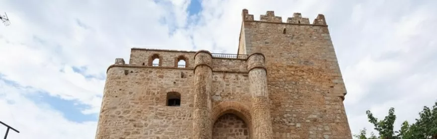 Construcción fortificada con muros gruesos, almenas y escaleras laterales de ladrillo.