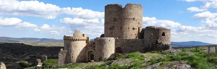 Vista aérea de un castillo rodeado de montes y formaciones rocosas.