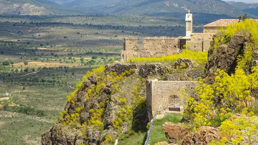 Edificación junto a una ladera rocosa cubierta de vegetación.