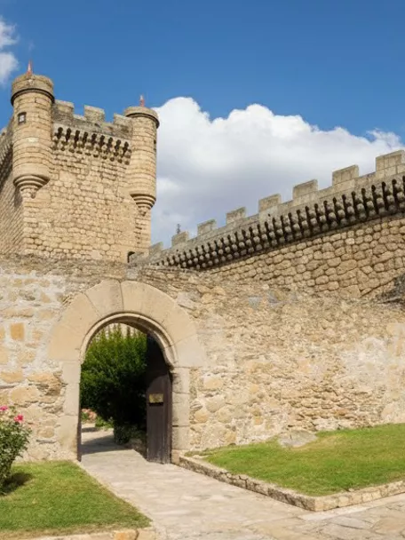 Muralla de piedra con torre circular y puerta de arco.