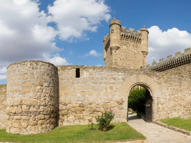 Muralla de piedra con torre circular y puerta de arco.