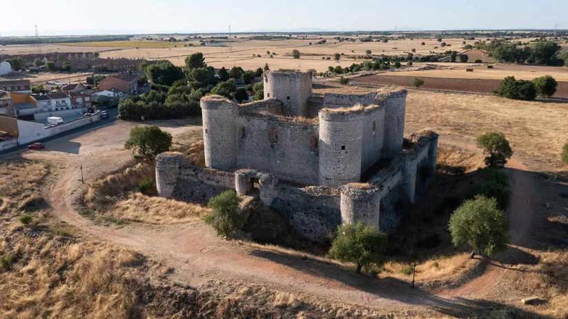 Vista aérea de un antiguo castillo rodeado de campos verdes en el campo