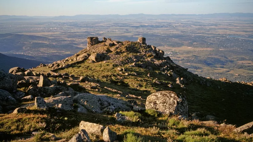 Castillo de piedra sobre colina rocosa con amplias vistas al valle.