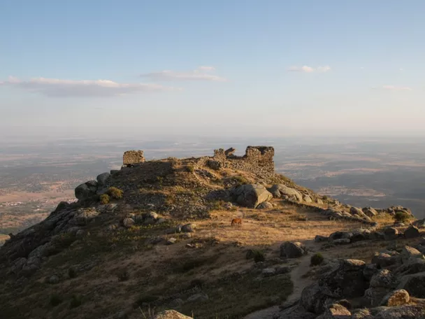 Ruinas de fortaleza en la cima de una montaña al atardecer.