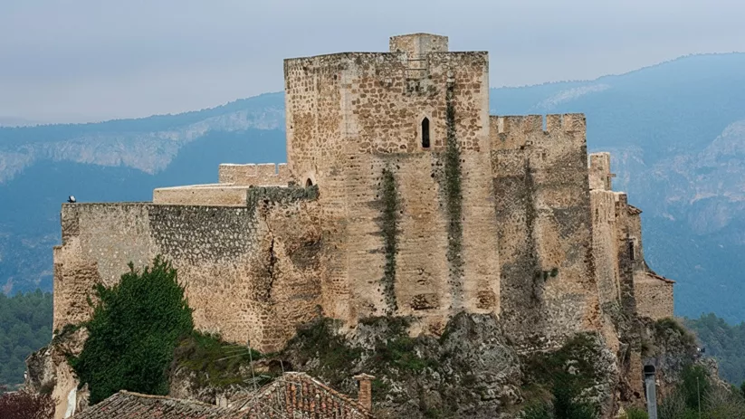 Detalle de fortaleza de piedra con torres y murallas.